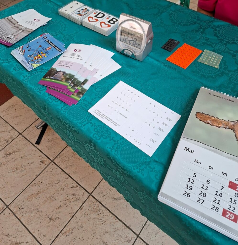 Tisch, auf dem verschiedene Hilfsmittel und Flyer verteilt liegen