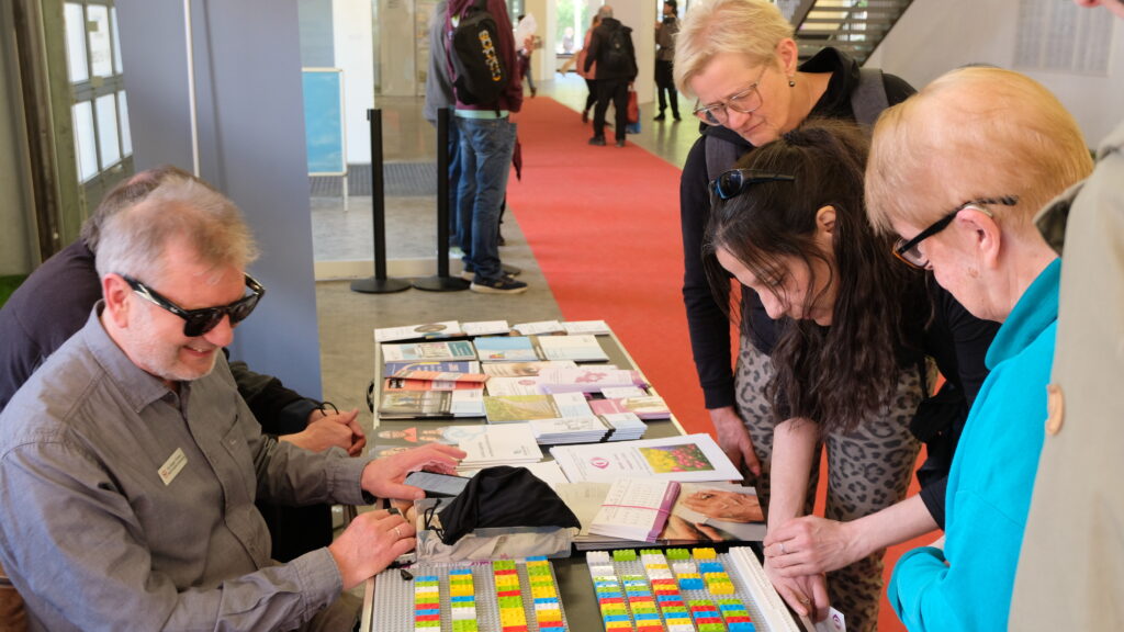 Jürgen Trinkus erklärt Interessierten am BSVSH Infostand das Braille Alphabet