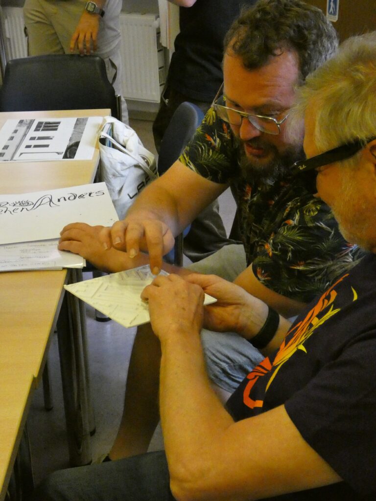 Christoph Kröger berührt ein Tastmodell eines Straßenplans, das Jürgen Trinkus ihm zeigt.